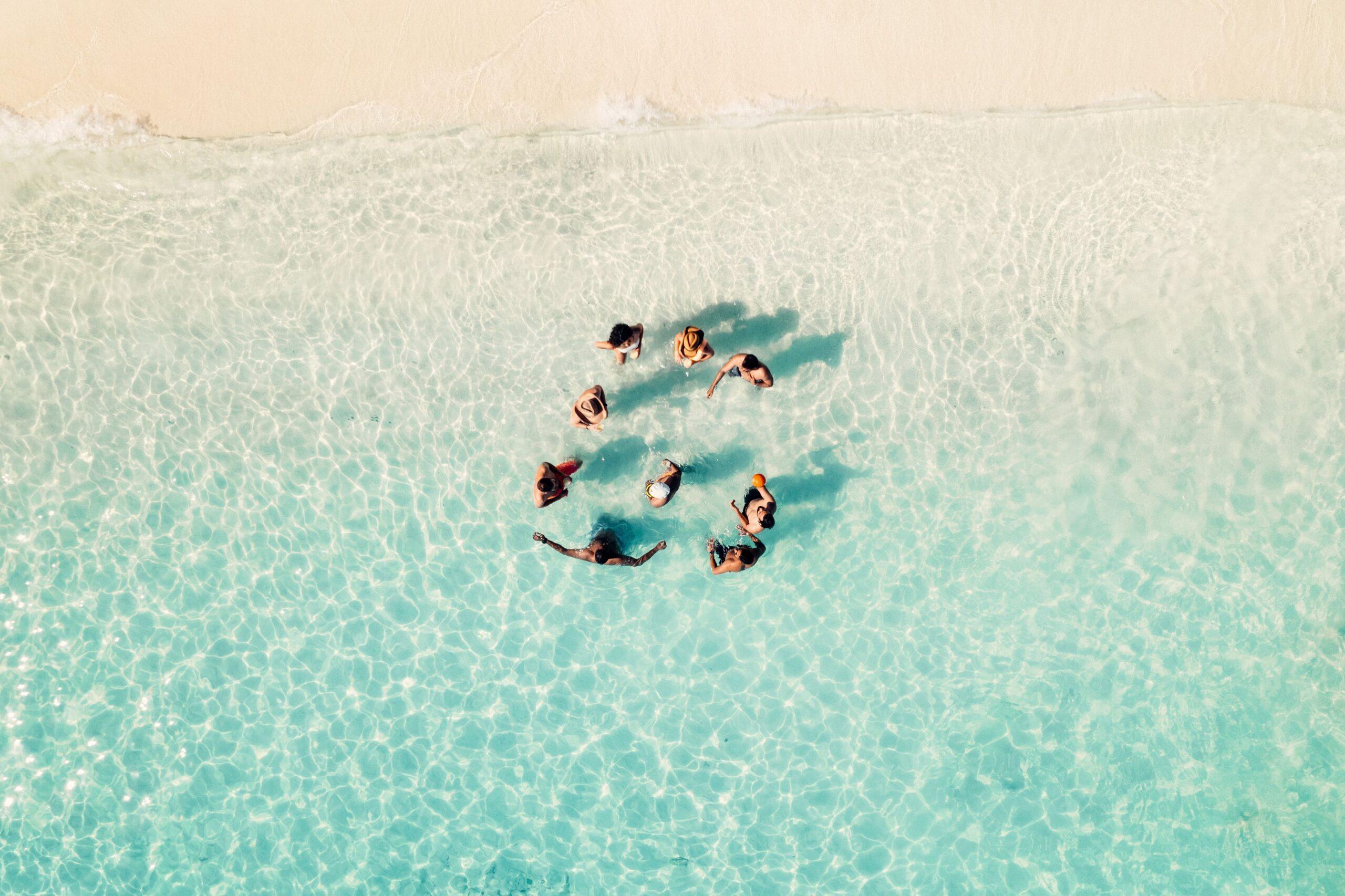 A sunlit sunset scene of friends relaxing and enjoying drinks on the deck of a sailing yacht in open ocean waters.